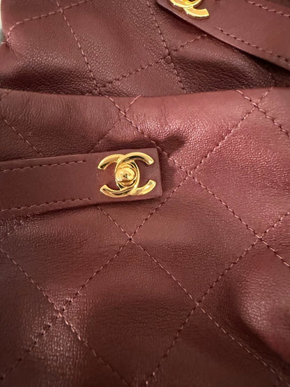 Chanel 26A burgundy backpack with buckle and leather gloves, size 7.5.
