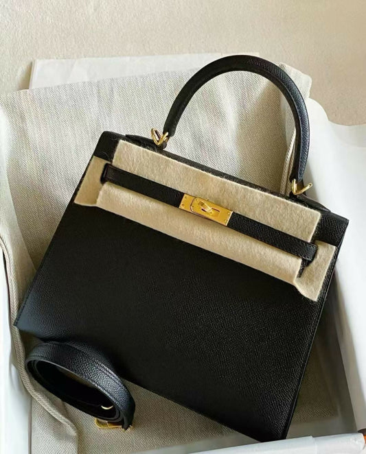 Black structured top-handle handbag in fine grained leather with gold-tone turn-lock hardware and detachable shoulder strap