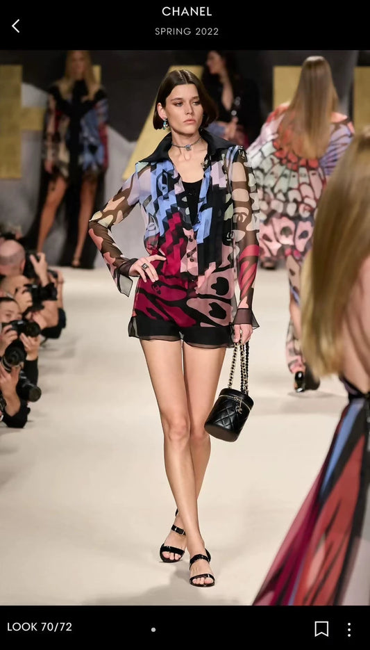 Model walking on a fashion show runway wearing a colorful outfit with 'Chanel' branding.