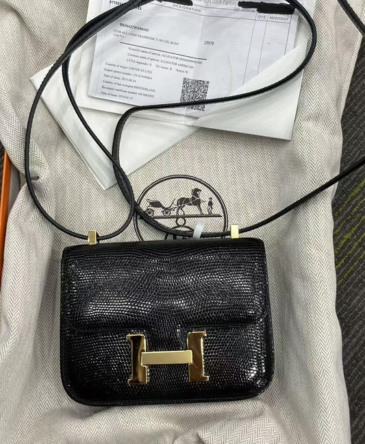 Hermès Constance crossbody bag in black lizard-embossed leather with gold H clasp and thin shoulder strap