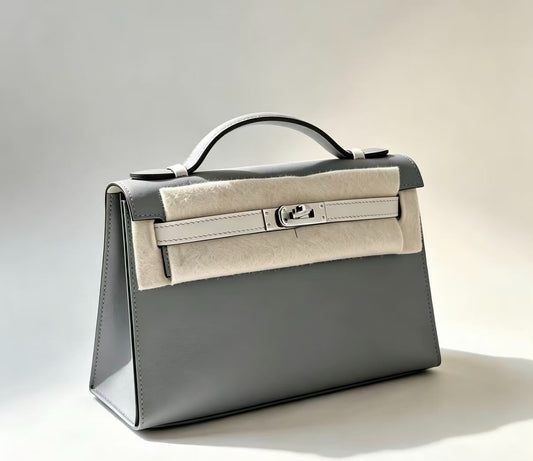 Grey leather clutch handbag with silver-tone turn-lock closure, pale cream strap and top handle