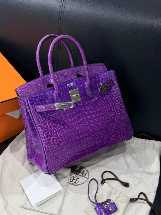 Purple glossy crocodile-pattern top-handle bag with silver-tone hardware, turn-lock closure and rolled handles