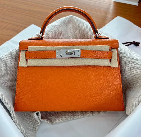 Orange Kelly mini handbag with palladium hardware, grained leather and single top handle
