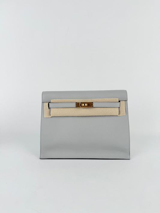Pale grey leather clutch with gold-tone turn-lock hardware and front strap, shown with a beige felt protector