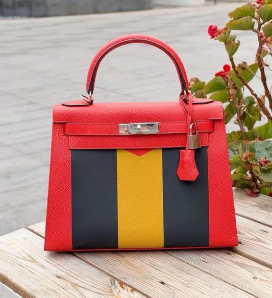 Red structured top-handle handbag with navy and yellow vertical stripe panel and palladium-tone hardware