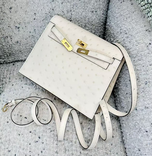 Cream white ostrich leather flap crossbody bag with gold-tone hardware and long thin shoulder strap